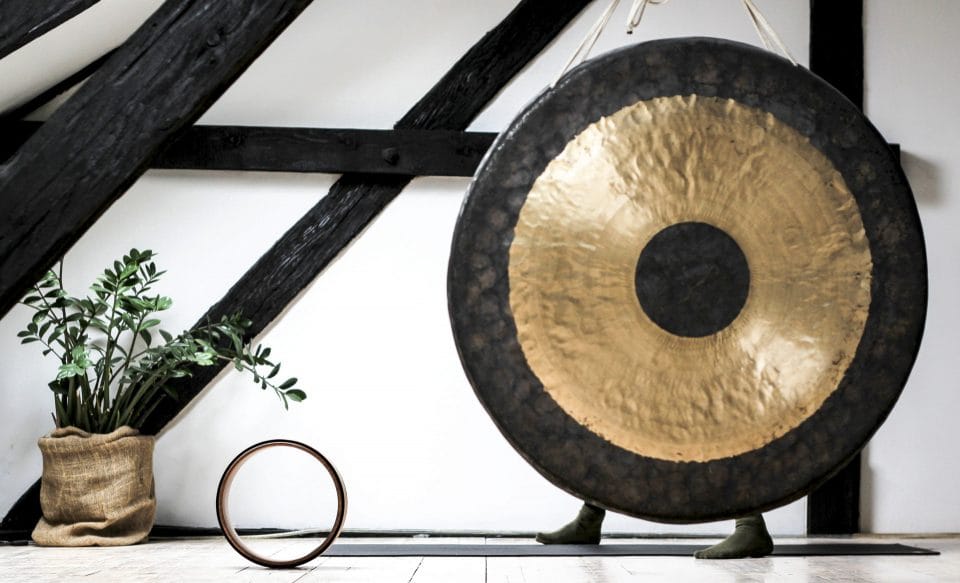 gong sitting a white and black room next to a yoga mat and plant