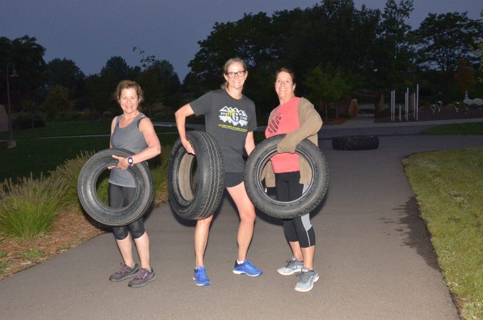 women holding tires and smiling at club greenwood summer boot camp