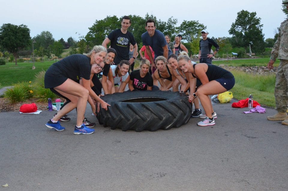 people smiling with big tire at club greenwood summer boot camp