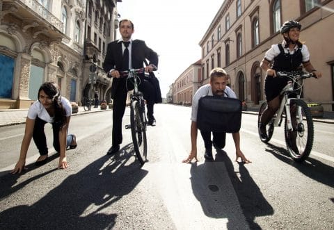 businessmen and women about to race in the street wearing suits