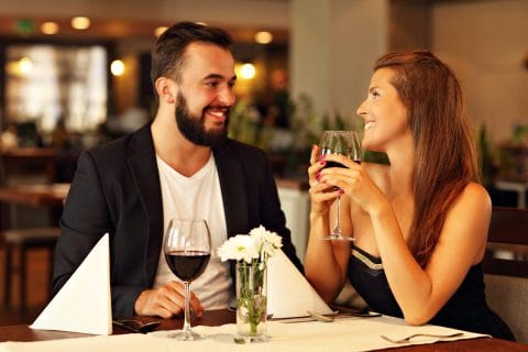 man and woman drinking wine at a restaurant for date night
