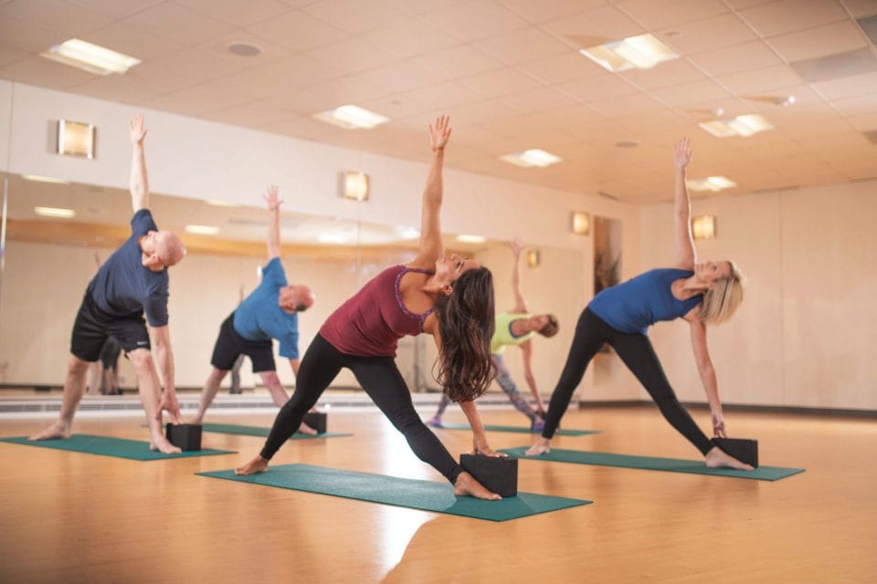 people doing triangle pose in club greenwood yoga studio