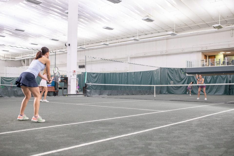 women playing tennis on club greenwood indoor clay court