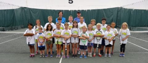 kids and coaches in a group photo for junior tennis camp smiling with tennis racquets