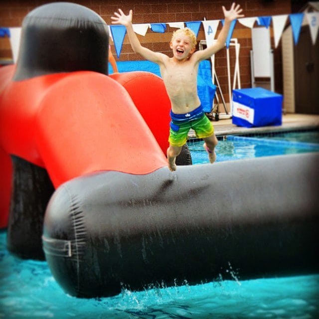 kid jumping off of club greenwood outdoor pool float