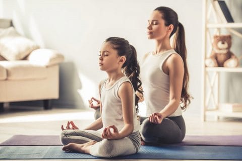 kid practicing yoga and meditation with her mom on yoga mats