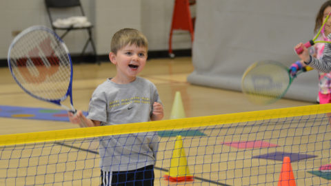 cute kids playing tennis and smiling during little lobbers class in club greenwood gymnasium