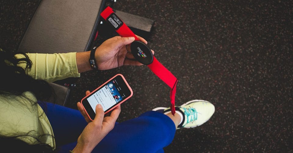 person holding a myzone belt and checking the MyZone App on their phone