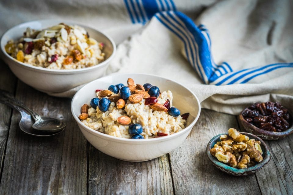 two bowls of oatmeal and a bowl of raisons and walnuts