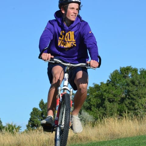 boy in purple hoodie riding his bike during the club greenwood kid's triathlon