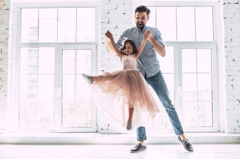 little girl in tutu dancing with her dad