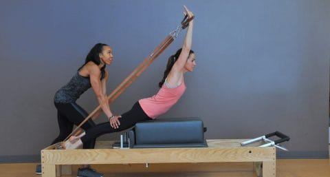 woman on reformer getting a private pilates lesson with an instructor