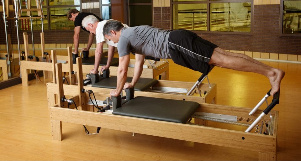 men doing pilates on reformers in a club greenwood pilates studio