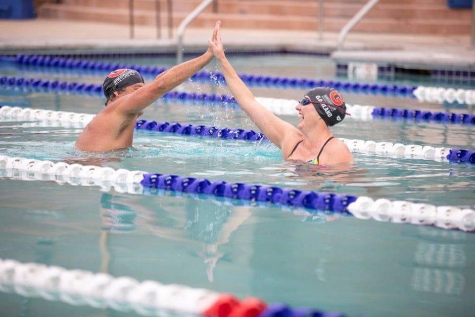 swimmers high five in pool lane in club greenwood outdoor pool