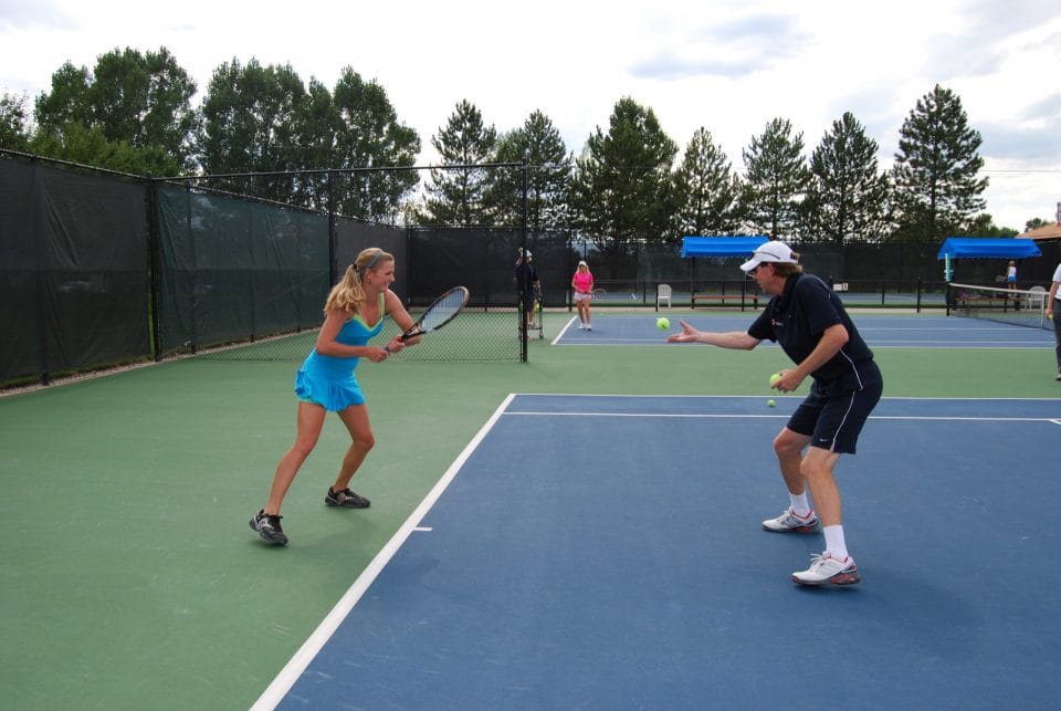 Ron steege club greenwood director of tennis coaching a student on the outdoor tennis courts