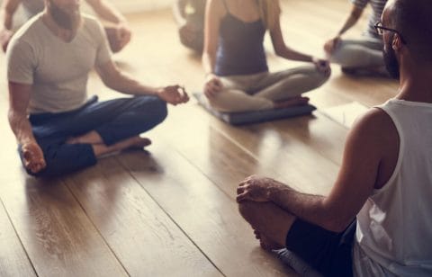 people sitting and meditating in a yoga studio in front of their teacher