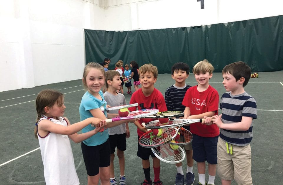cute kids holding tennis racquets and tennis balls in circle smiling