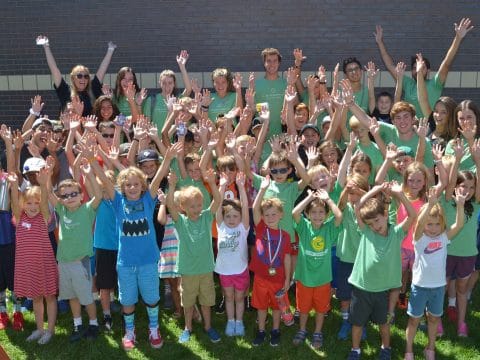 kids having fun with their arms up at summer camp with camp counselors