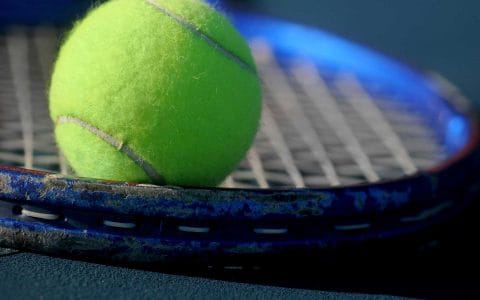 yellow tennis ball sitting on a tennis racquet