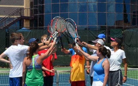 teens putting racquets in the air an outdoor court