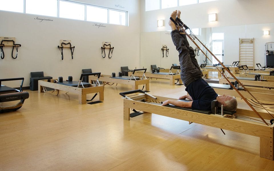 man doing pilates in a studio on a pilates reformer