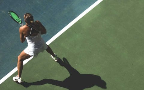 overhead view of woman playing tennis outside