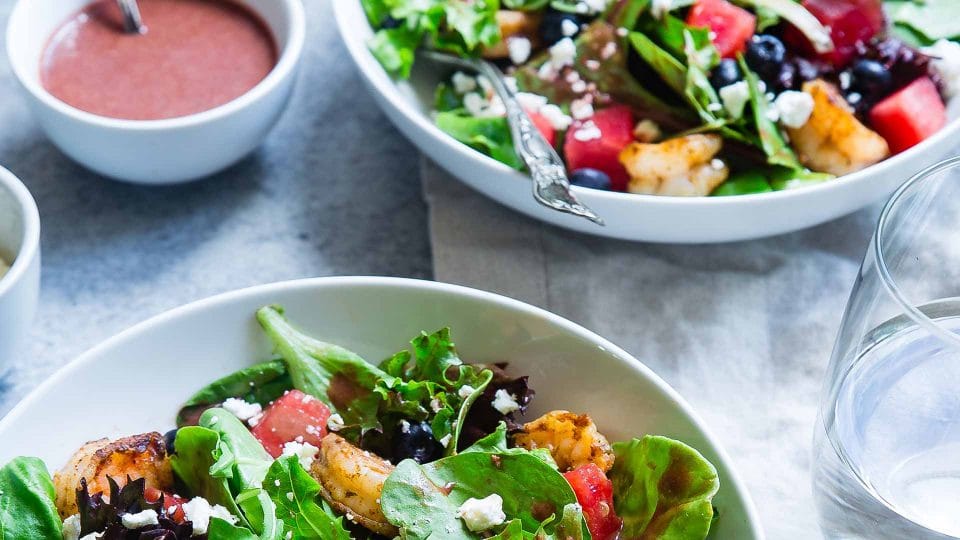 salads on a table with salad dressing and a glass of water