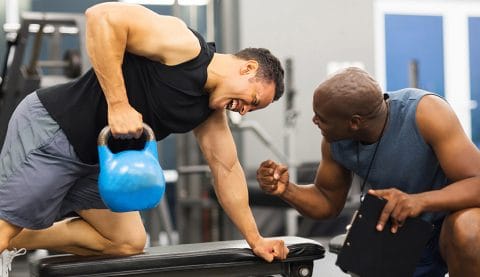 personal trainer training man with heavy kettle bell