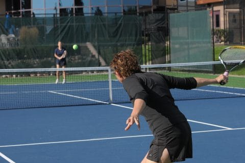 woman hitting a tennis ball on outdoor court