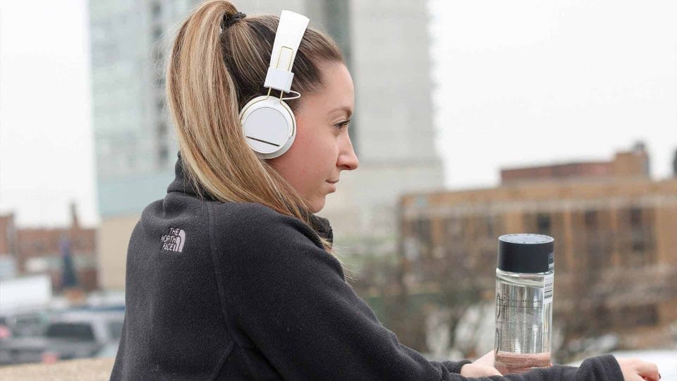 woman on rooftop listening to music and drinking water in north face jacket