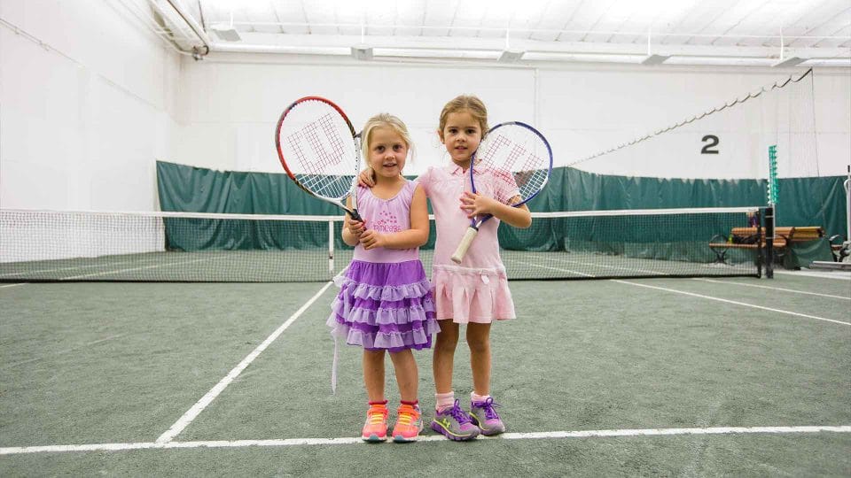 little girls and their tennis racquets on an indoor court