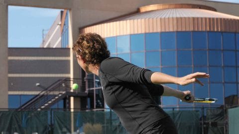 woman hitting a tennis ball on outdoor court