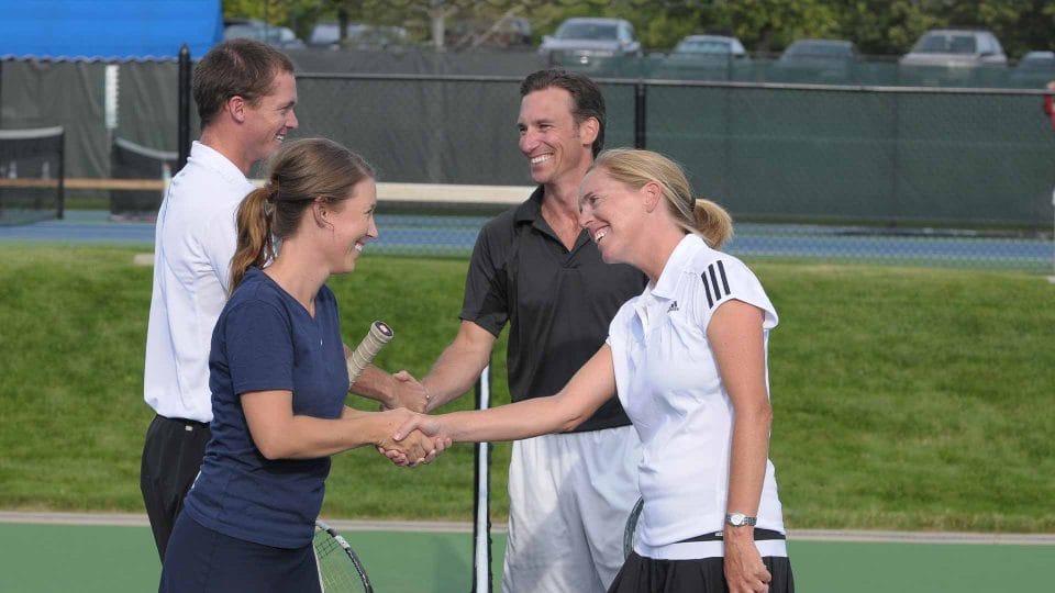 people shaking hands after a tennis match on an outdoor court