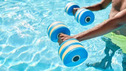 man holding foam water dumb bells in pool