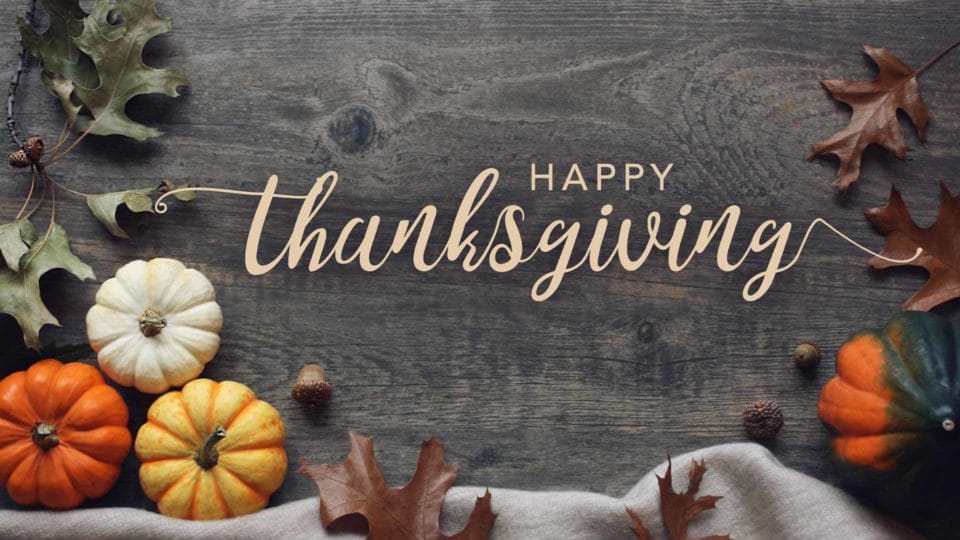 holiday background with pumpkins and leaves with text that says happy Thanksgiving