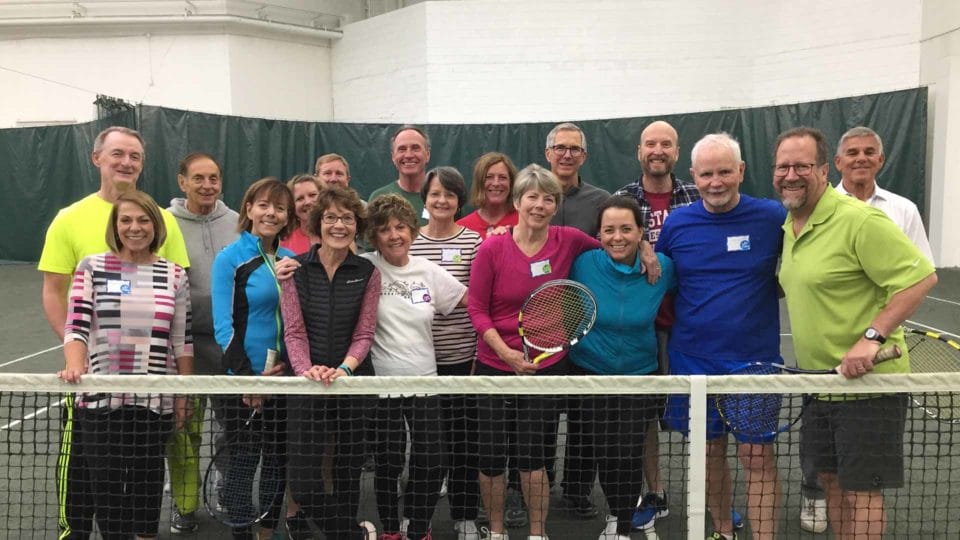 group of people smiling on club greenwood tennis court