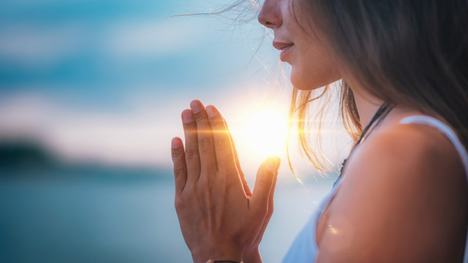 Woman with her hands together by her heart, meditating