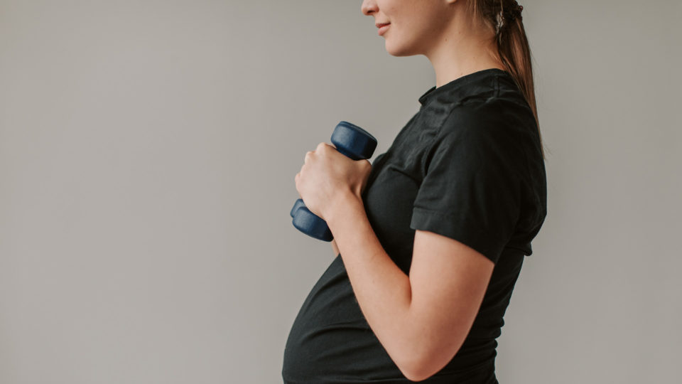 Pregnant Woman holding weights above her belly