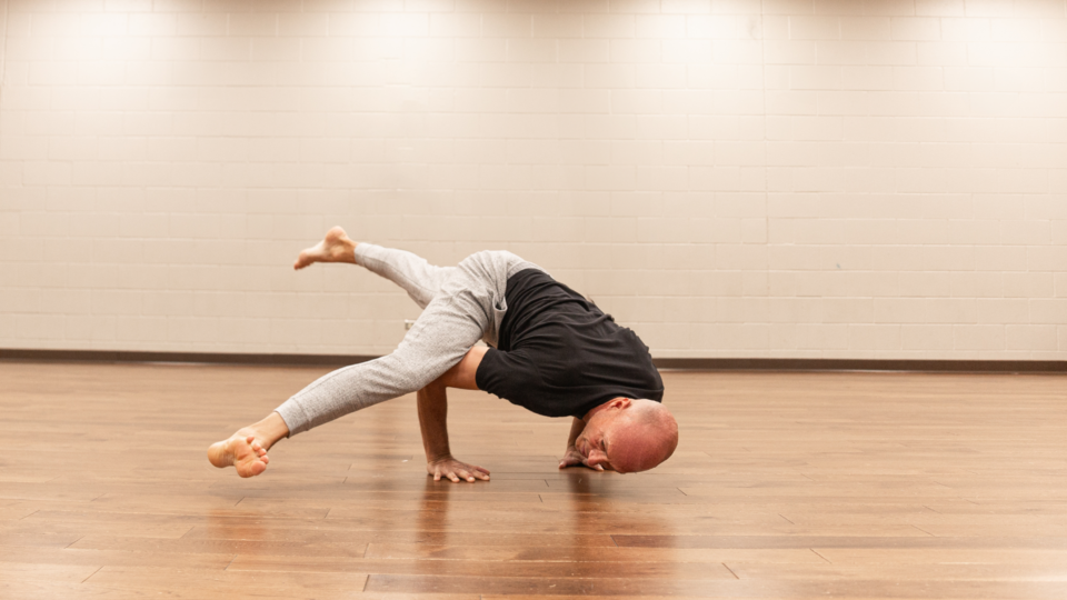 club greenwood male yoga instructor performing arm balance in studio