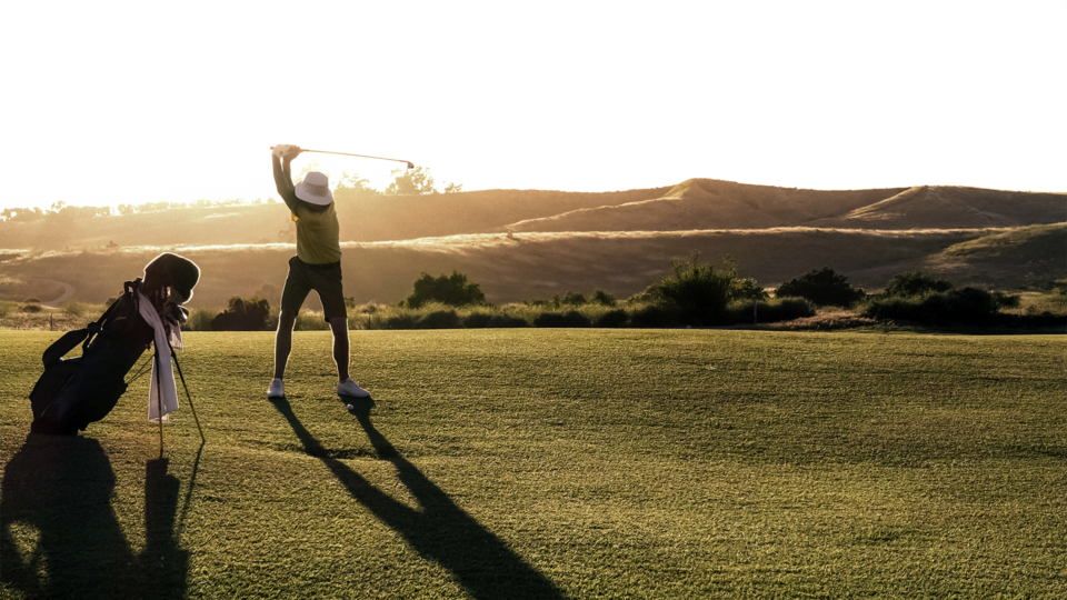 man playing golf at sunset