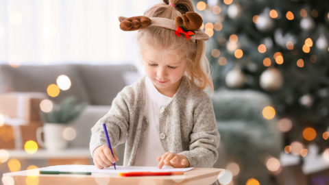 Cute little girl writing letter to Santa at home