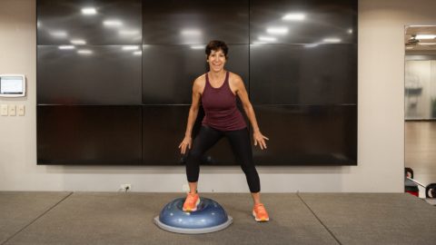 female brunette instructor using a bosu ball in a studio