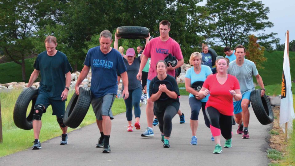 group of people working out outside in outdoor boot camp with tires