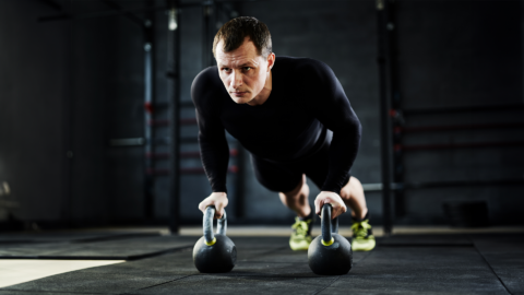 man performing pushup with kettlebells in a crossfit studio