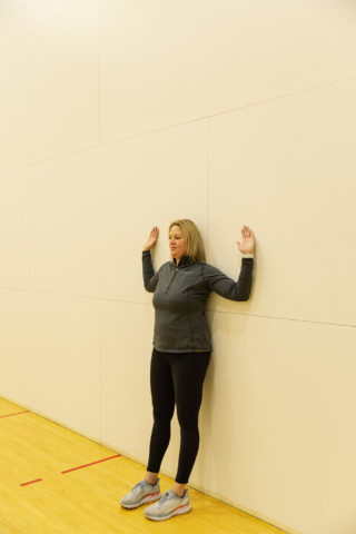 club greenwood personal trainer performing a wall stretch