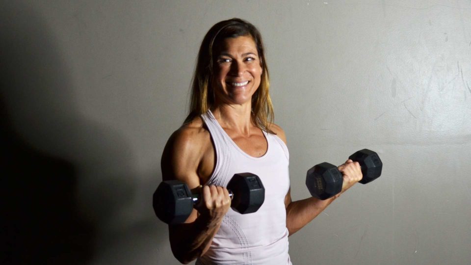club greenwood personal trainer michelle yost lifting dumbbells and smilling