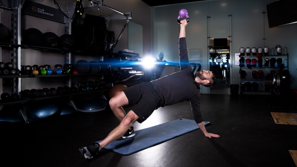 male personal trainer performing a mobility movement in a studio