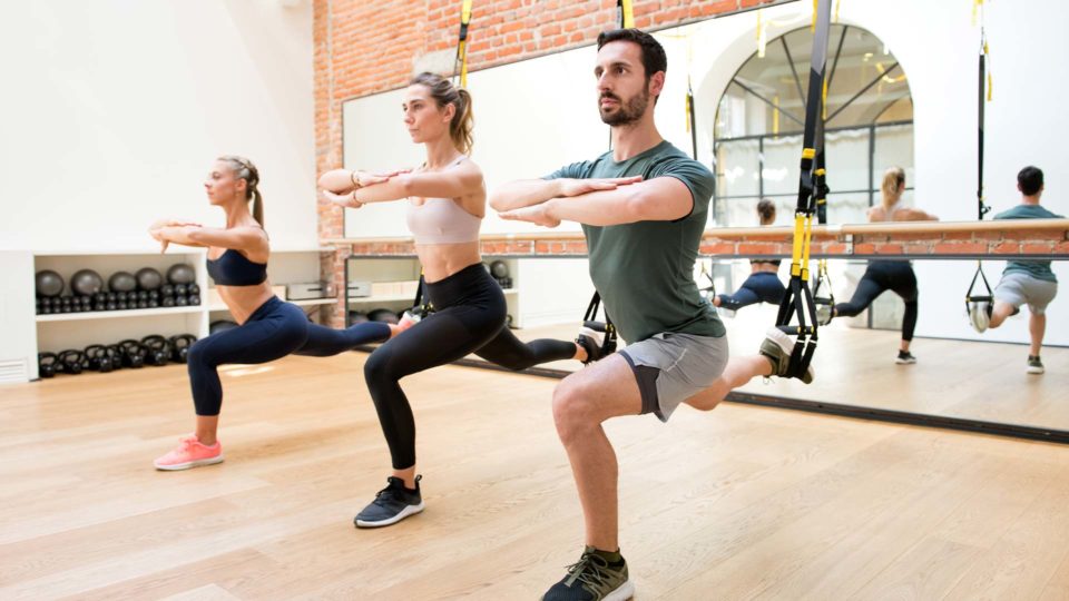 people working out in a pilates studio using TRX