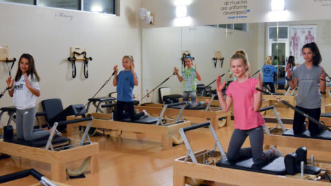 pilates for teens class at club greenwood with teenagers smiling on pilates reformers