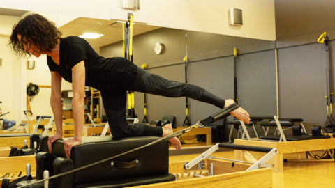 woman pilates instructor on reformer in studio